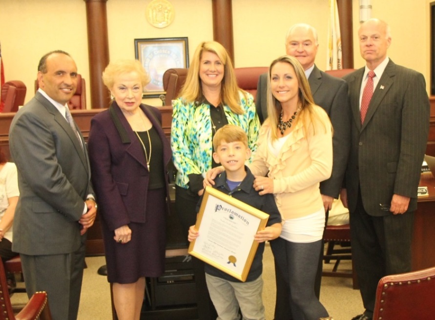 The Monmouth County Board of Chosen Freeholders present a proclamation to commemorate Prader-Willi Syndrome (PWS) Awareness Month to Cole Lombardi, who has been diagnosed with PWS and his mother, Tracy Lombardi on May 22, 2014 in Freehold, NJ. Pictured left to right: Freeholder Thomas A. Arnone, Freeholder Lillian G. Burry, Freeholder Serena DiMaso, Cole Lombardi, Tracy Lombardi, Freeholder John P. Curley and Freeholder Deputy Director Gary J. Rich, Sr.